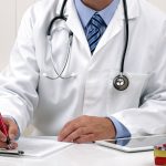 Doctor writing patient notes on a medical examination form or prescription